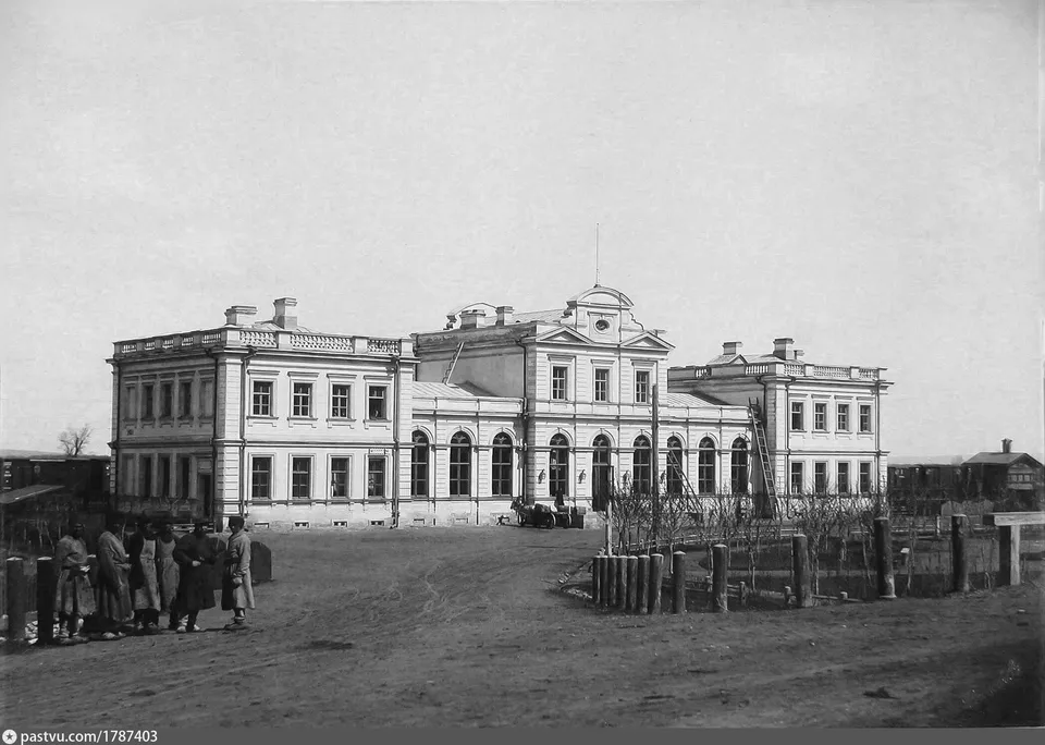Двухэтажное каменное здание вокзала XIX века, группа людей у входа