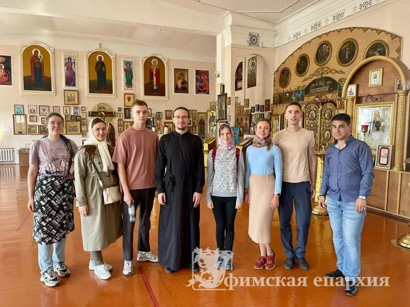 Группа людей и священник у иконостаса и стен с иконами внутри Никольского вокзального храма